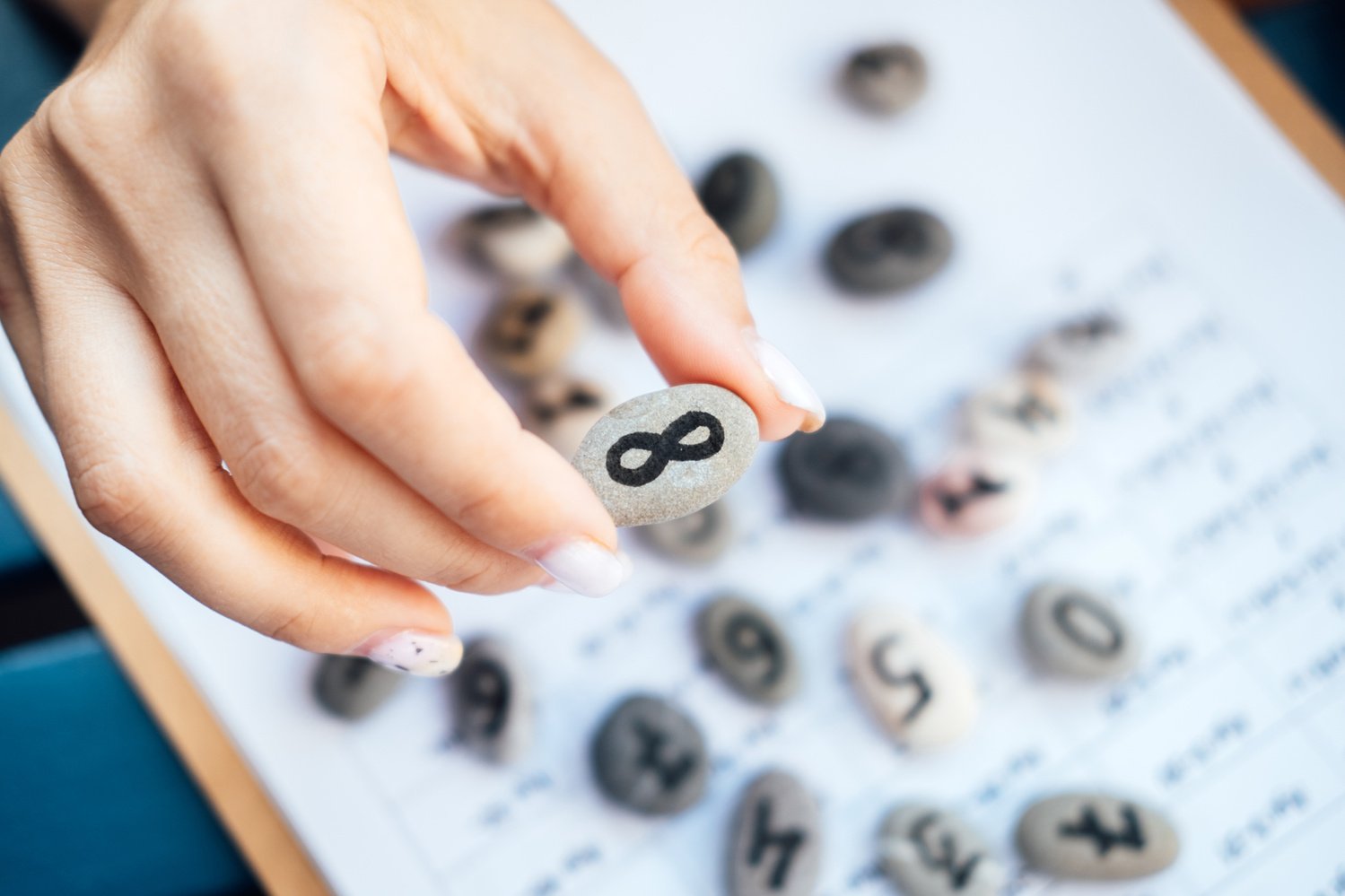 Woman numerologist hand with pebble stone with Infinity symb